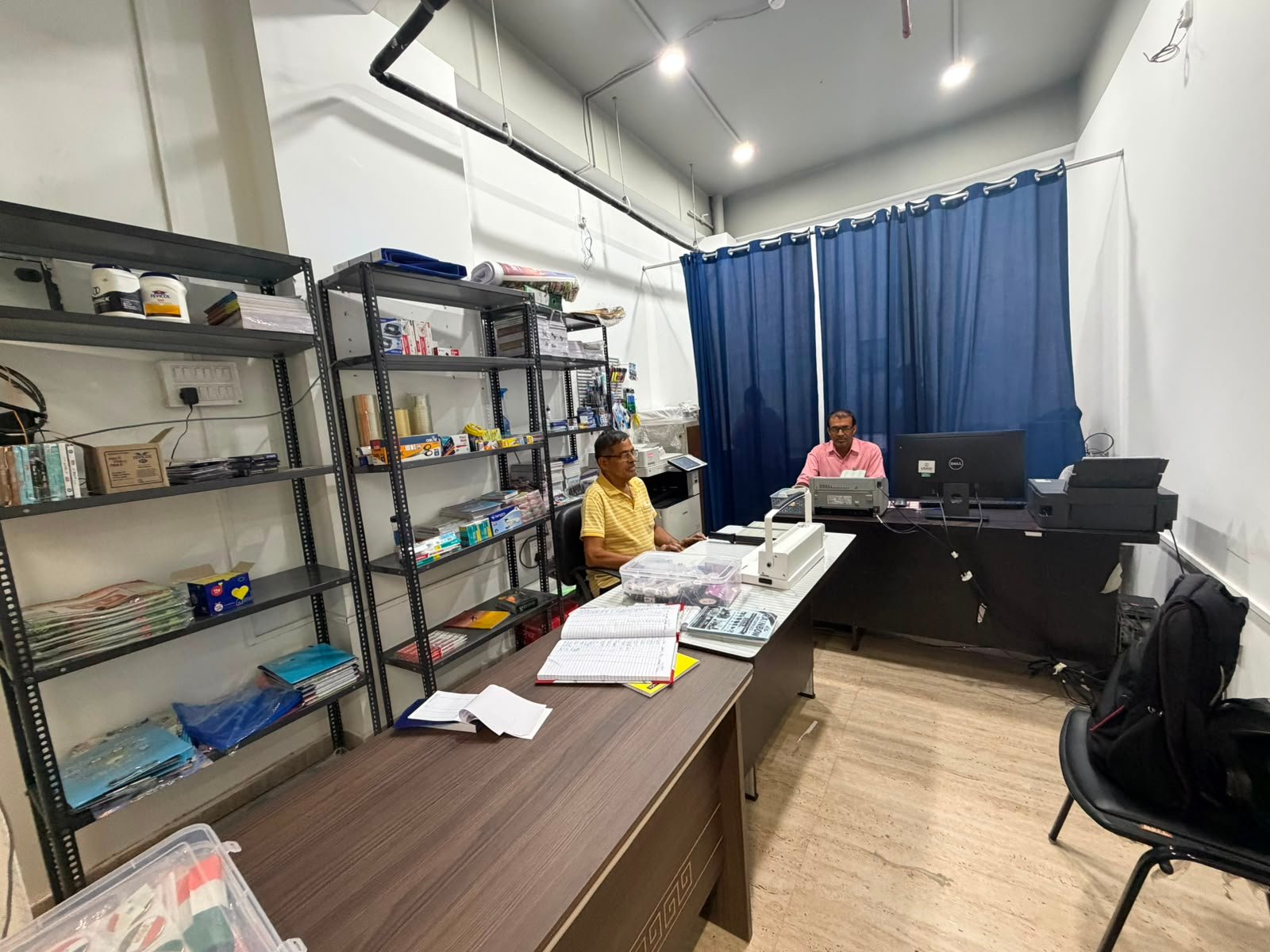 Staff operating binding and finishing equipment at service counter.